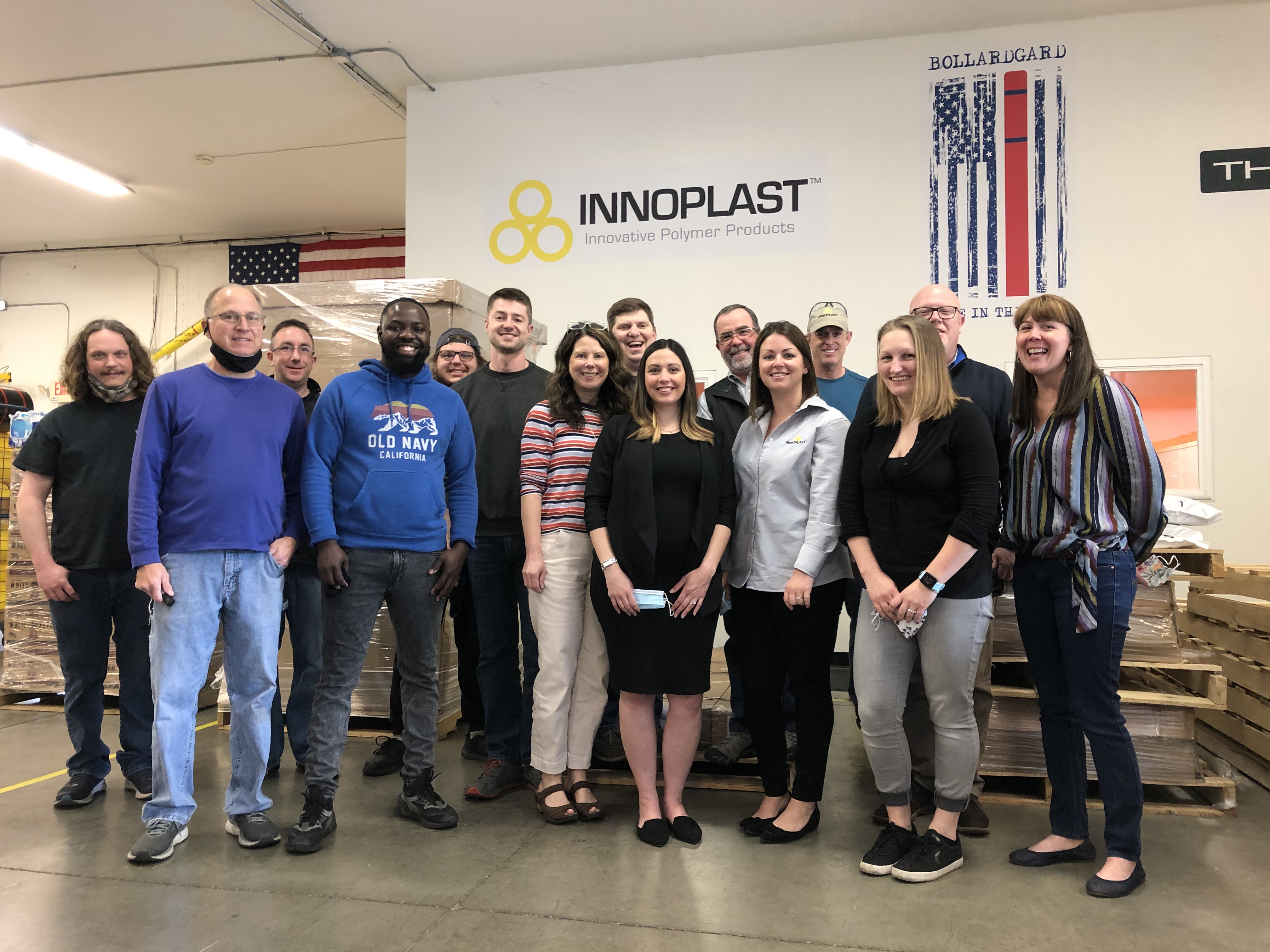 The Innoplast Team in the warehousing posing in front of the company logo